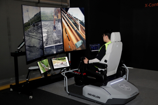 무인 굴착기를 사용자가 원격조종 스테이션에 앉아 조종하고 있는 모습. HD현대사이트솔루션 제공